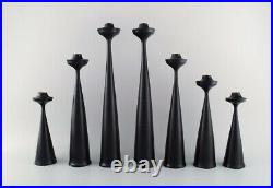 A collection of seven Scandinavian designer candlesticks in wood and brass