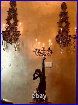 Classic set of floor candlestick held by a person, a pair of hanging candelabra
