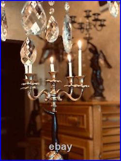 Classic set of floor candlestick held by a person, a pair of hanging candelabra